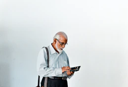 A man in a dress shirt and suspenders holding a tablet