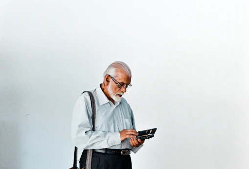 A man in a dress shirt and suspenders holding a tablet
