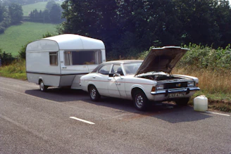 a car with a camper on the back of it parked next to a truck