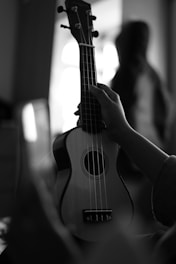 a black and white photo of a person holding a ukulele