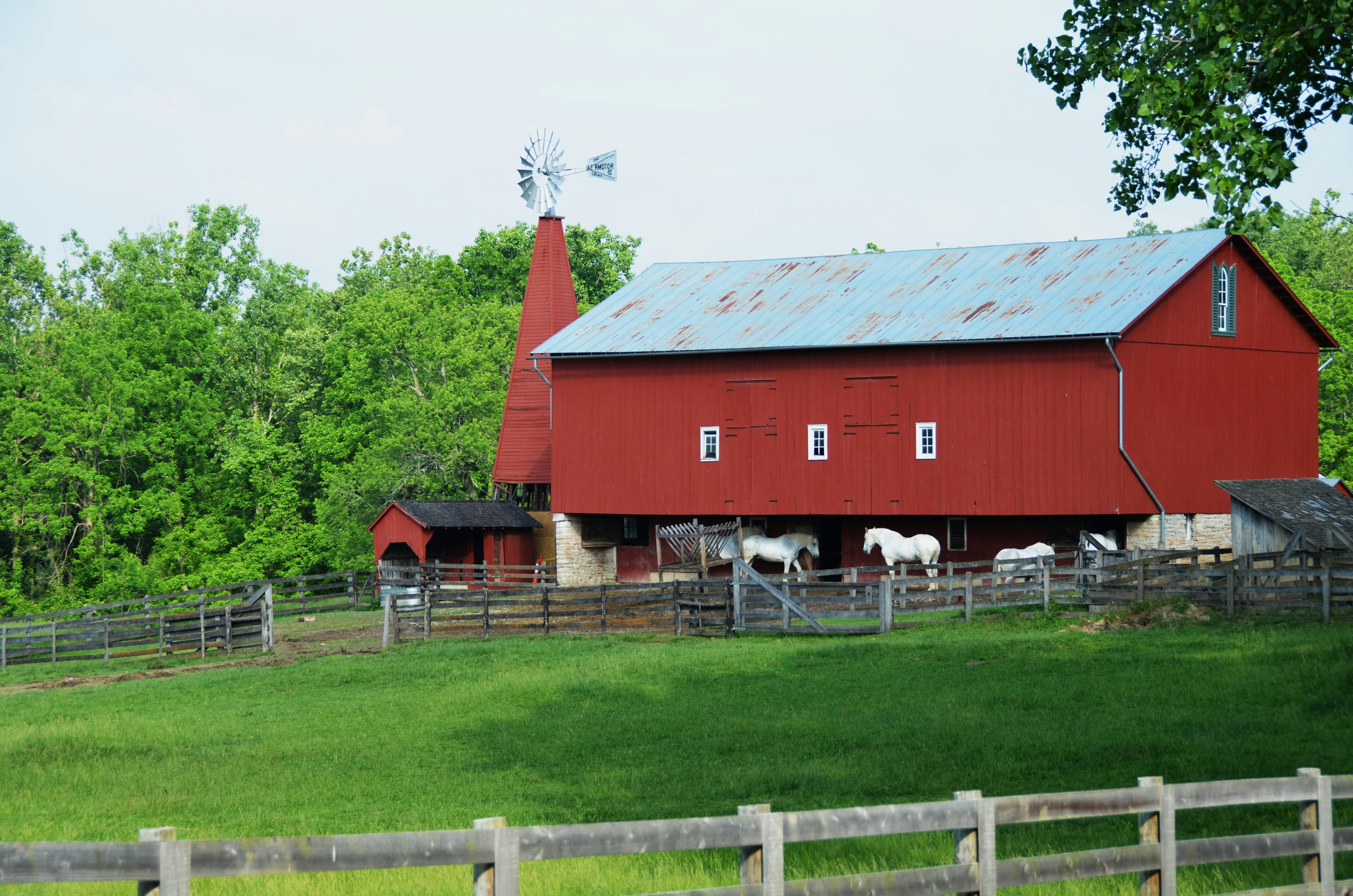 a red barn with horses in it and a windmill on top of it