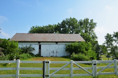 a white barn sits behind a white fence