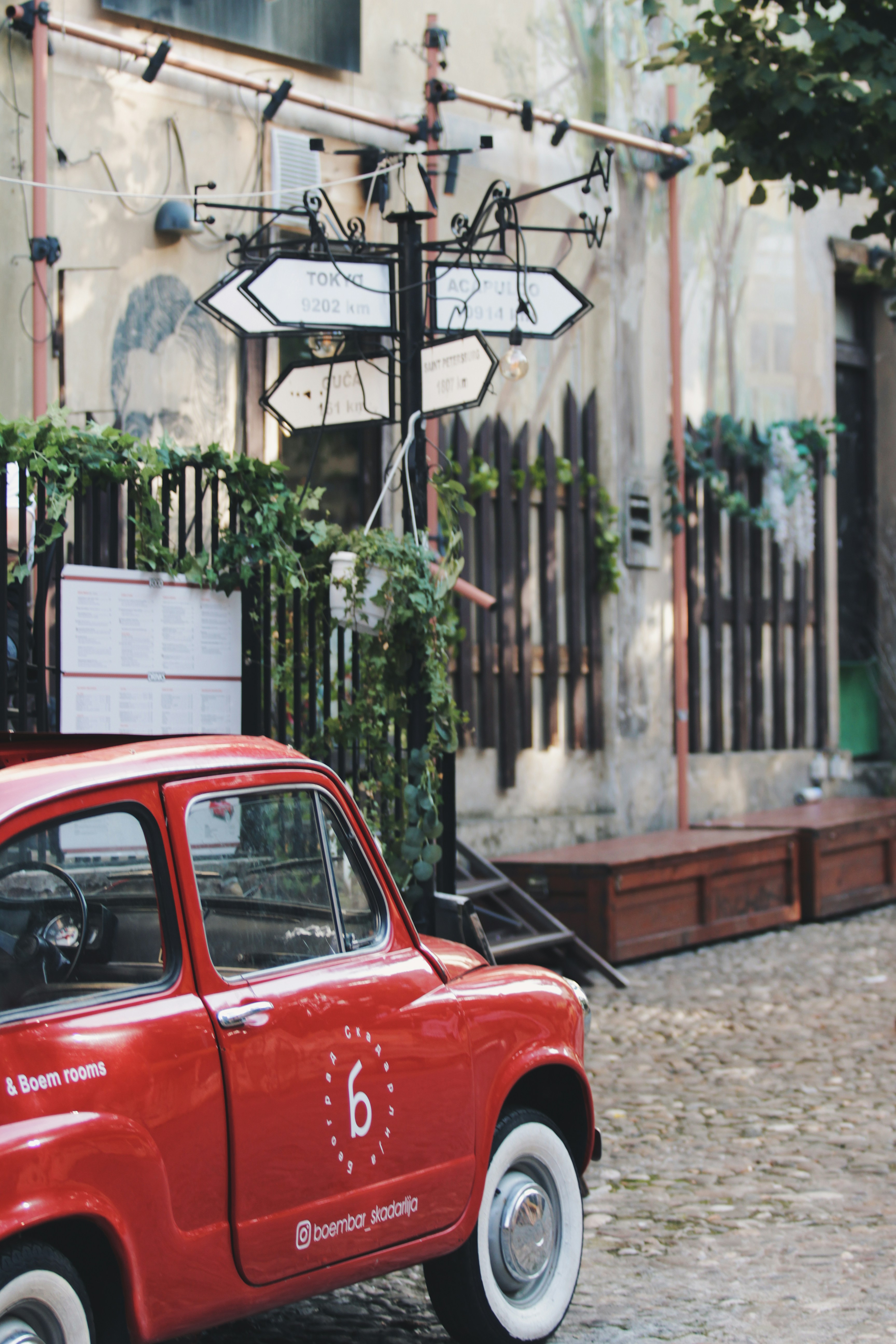 a small red car parked on a cobblestone street