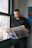 a man standing in front of a window reading a newspaper