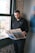 a man standing in front of a window reading a newspaper