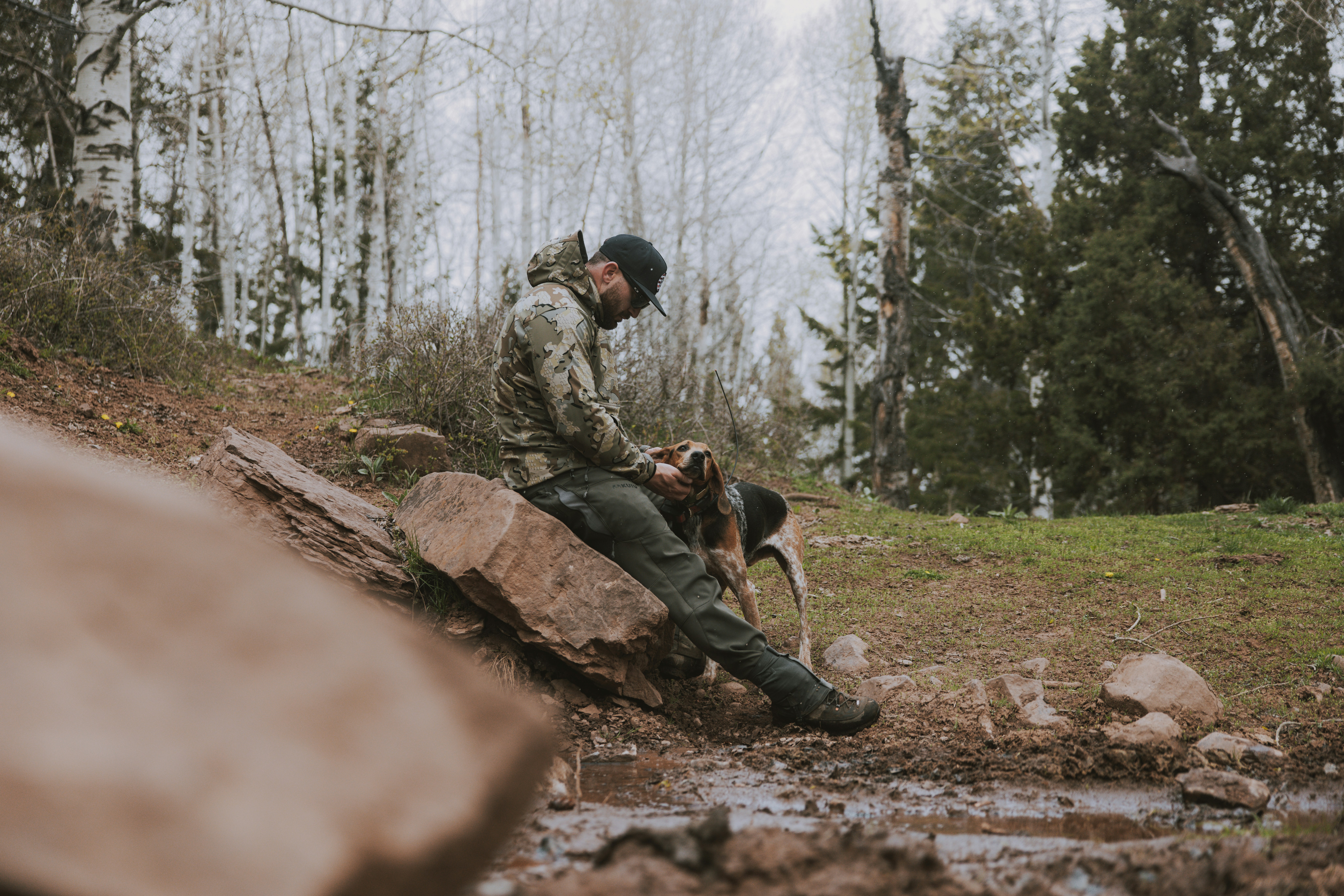 a man sitting on top of a rock next to a dog