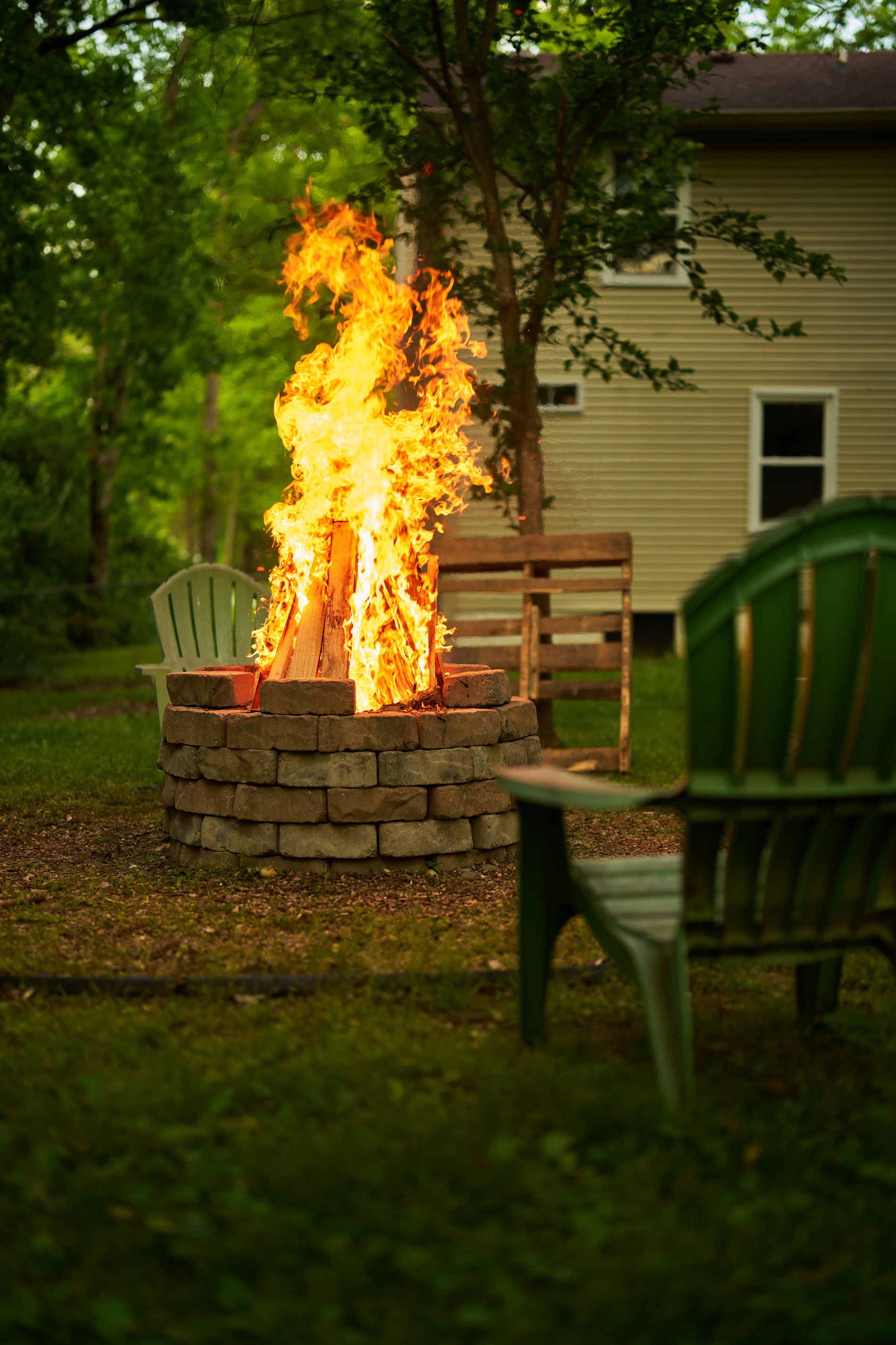 Stone backyard fire pit with tall flames and outdoor seating
