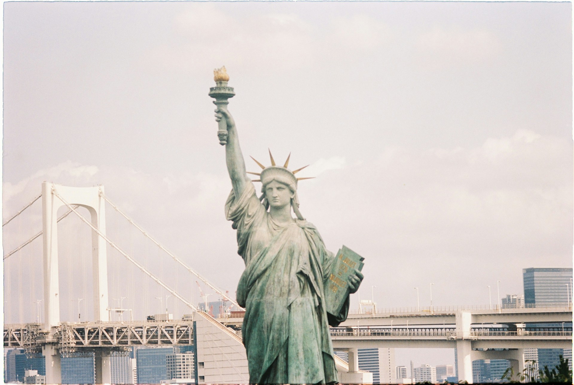 the statue of liberty stands in front of a bridge