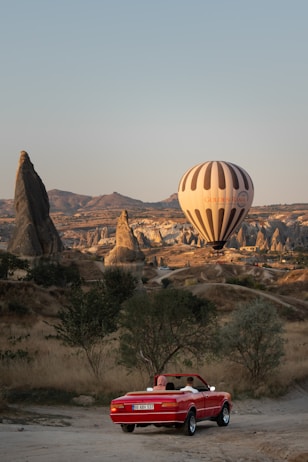 a red convertible car parked in front of a hot air balloon