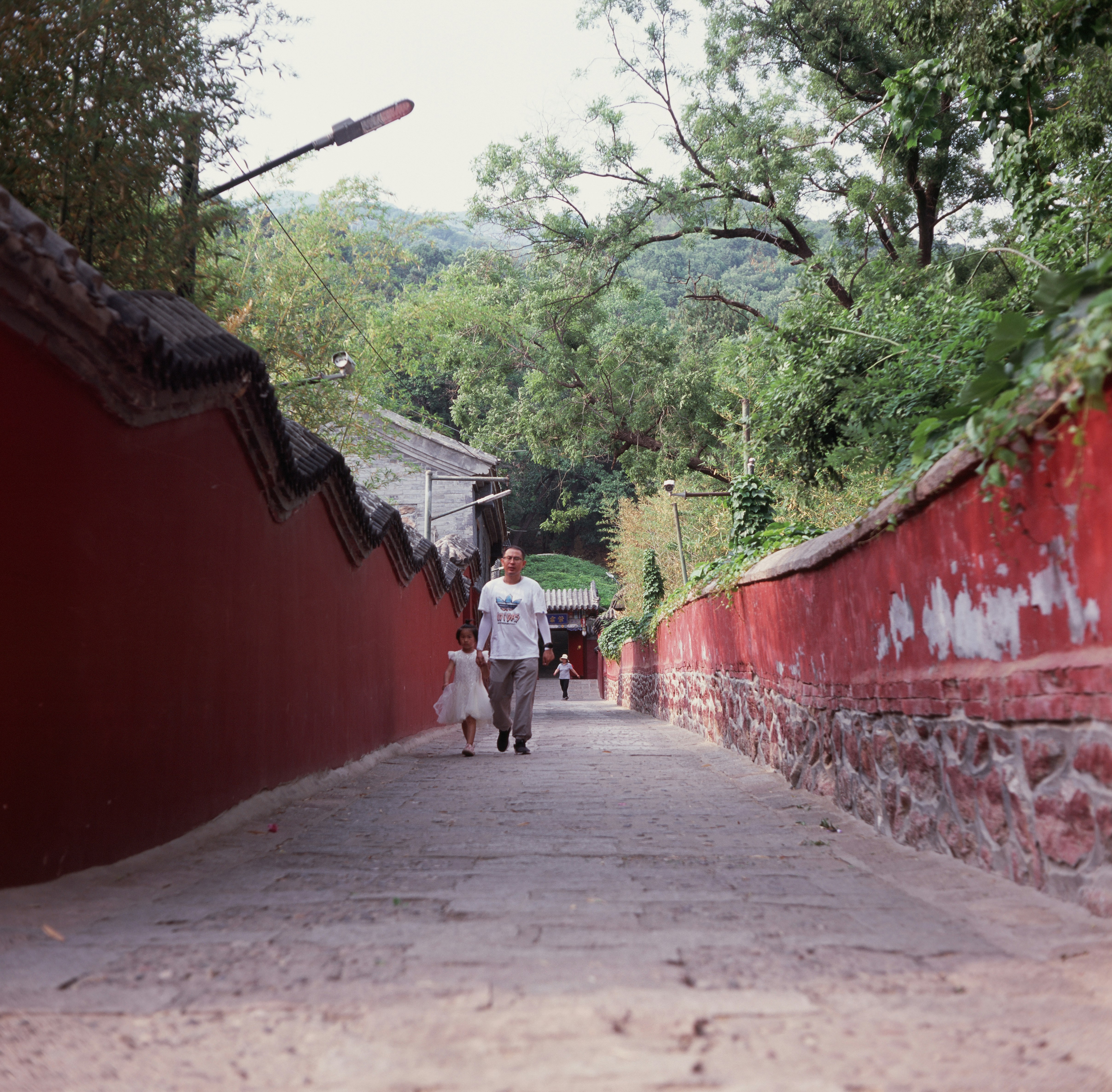 un homme marchant dans une rue à côté d’un mur rouge