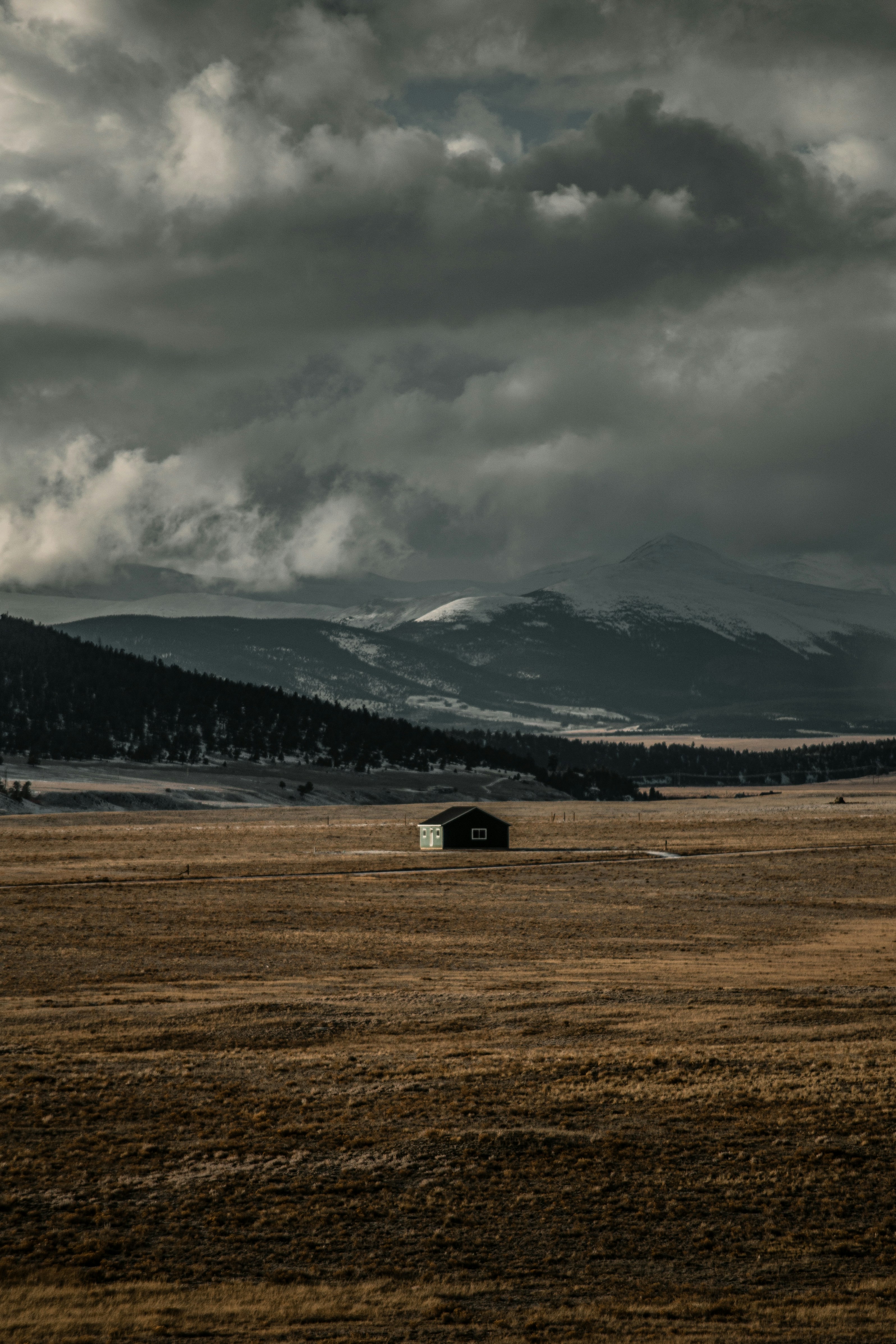un champ avec une grange et des montagnes en arrière-plan