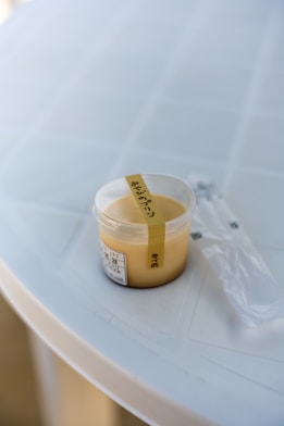 a container of mustard sitting on top of a white table