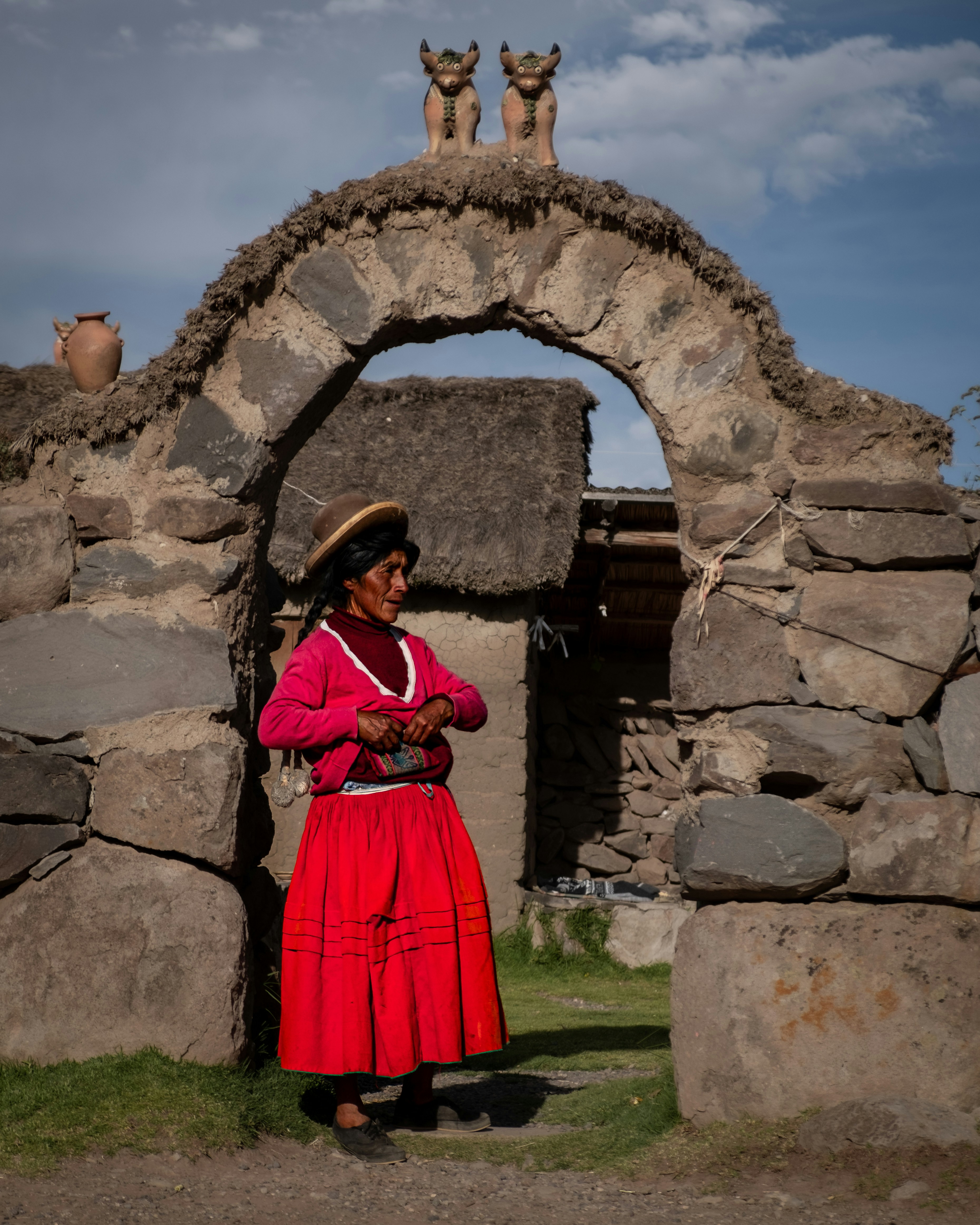 une femme en robe rouge debout devant une arche de pierre