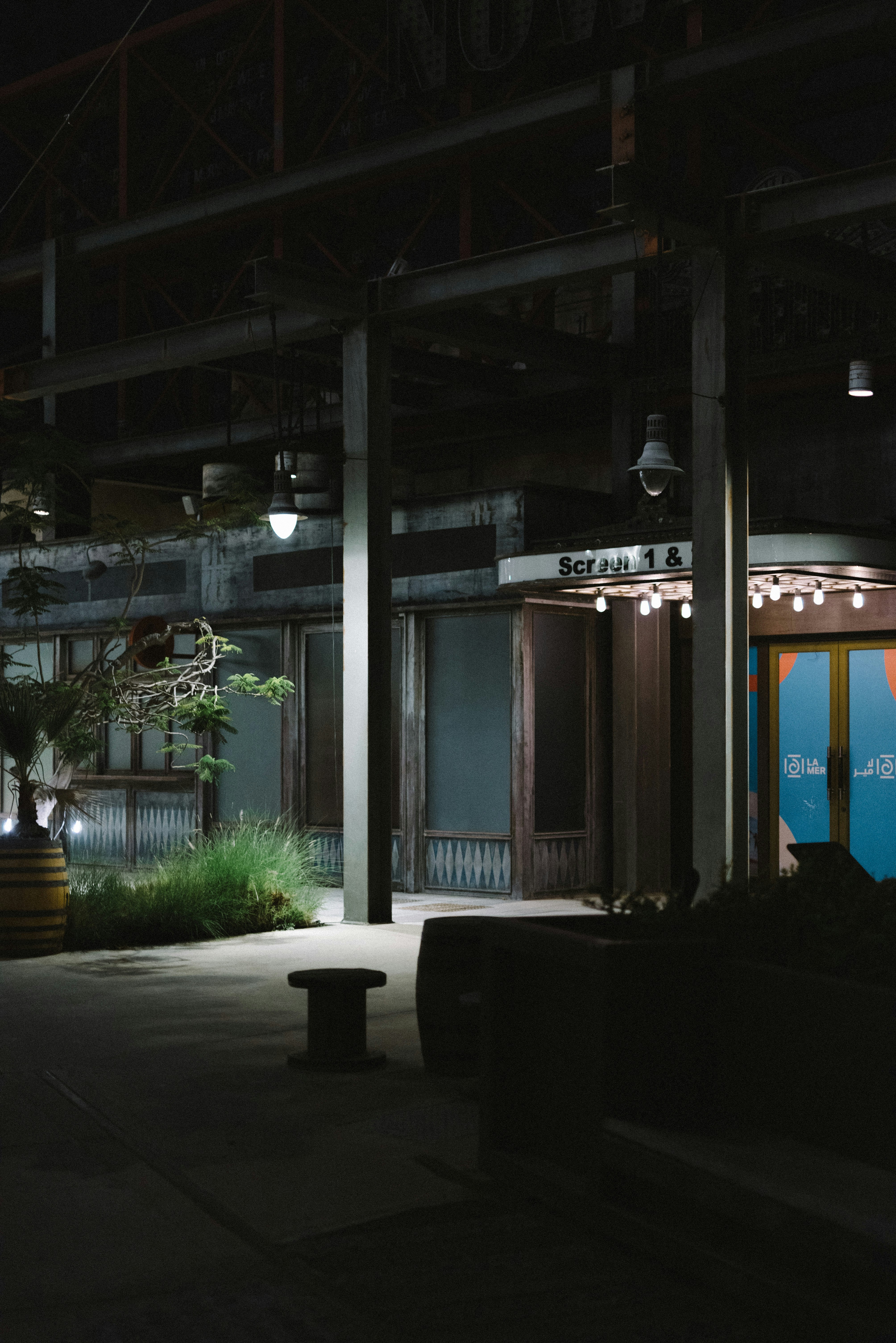 ein nachts beleuchtetes Gebäude mit einer Bank davor