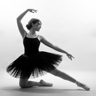 a woman in a black leotard and ballet shoes