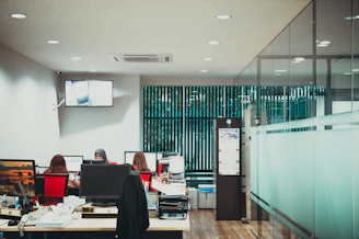 a group of people sitting at desks in an office