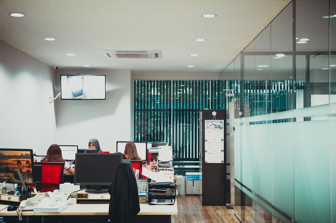 a group of people sitting at desks in an office,