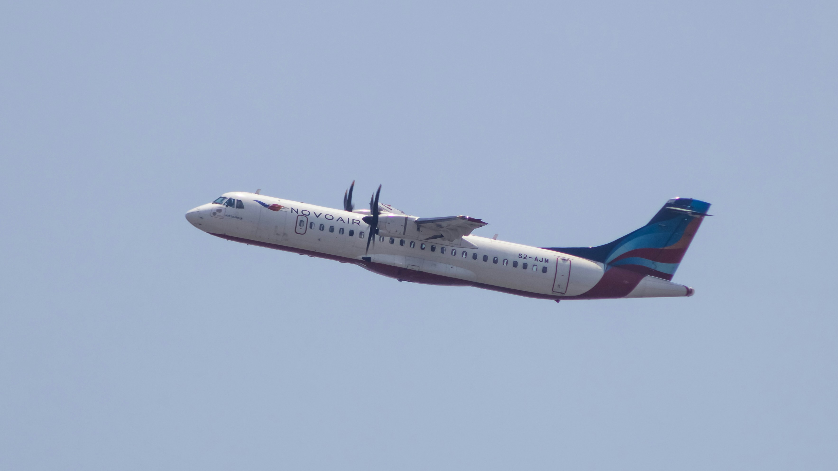 a large jetliner flying through a blue sky, Novoair ATR72-500