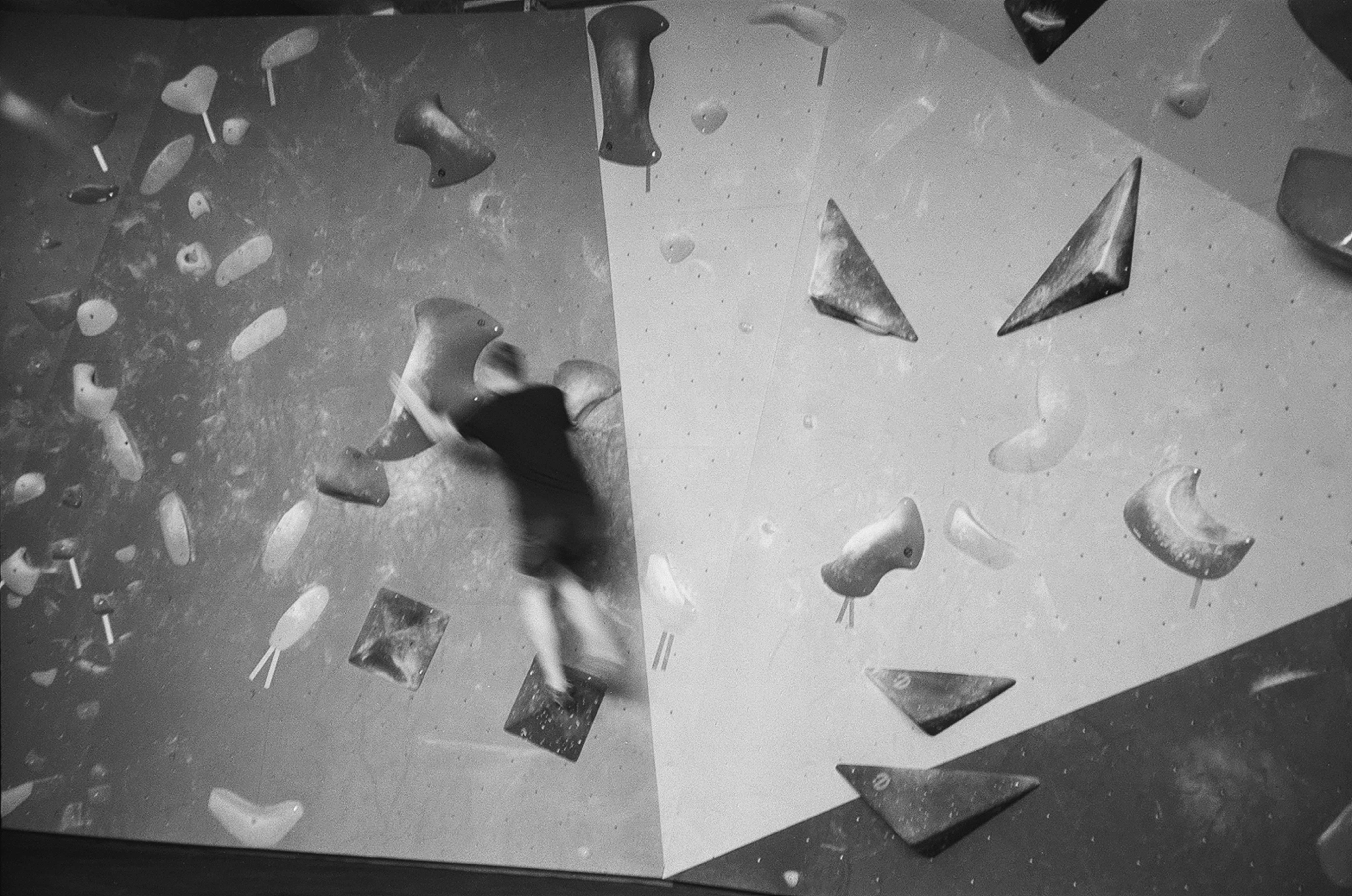 a black and white photo of a person climbing on a rock wall
