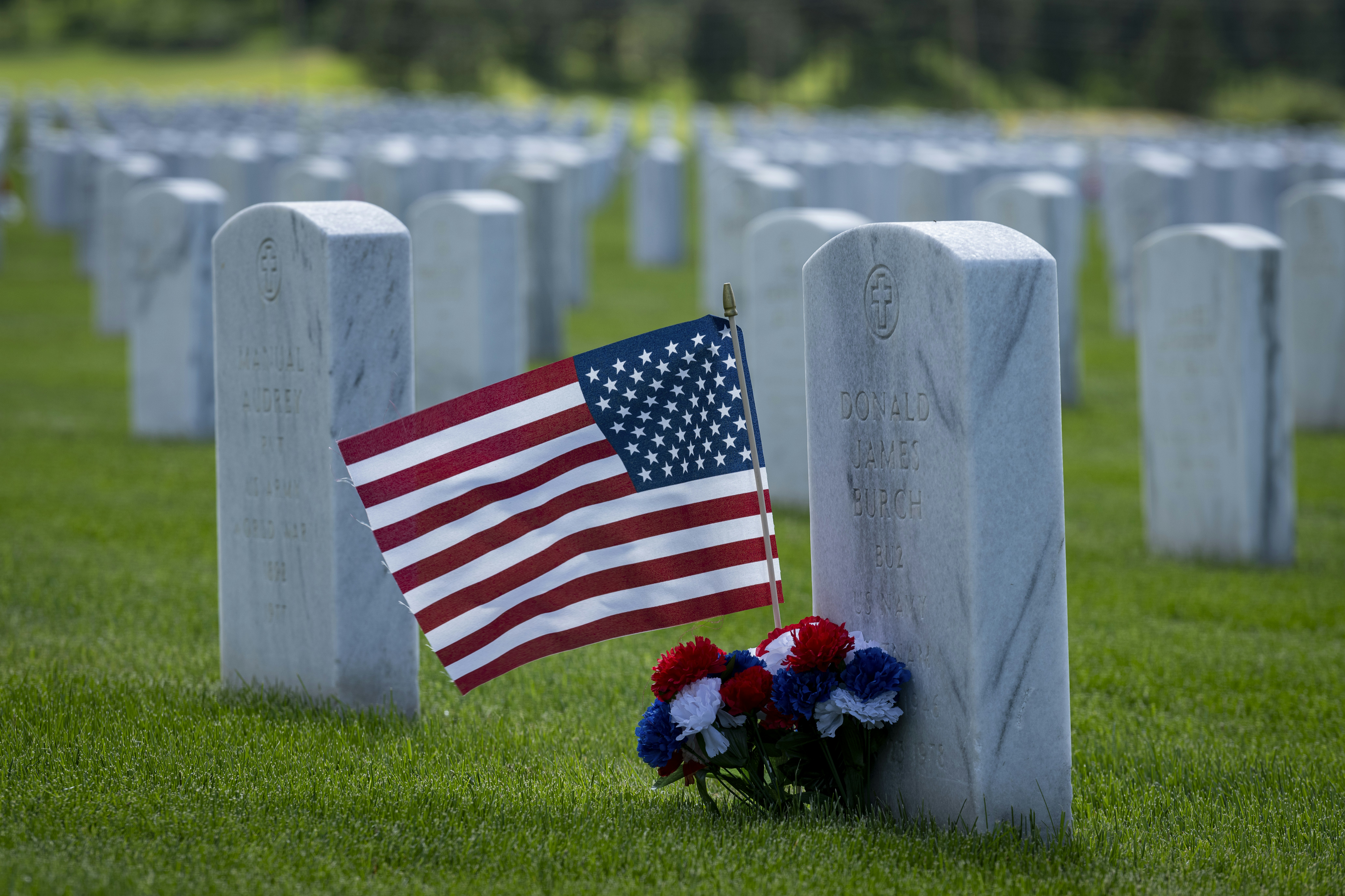 a flag and flowers are placed at the headstones of a cemetery