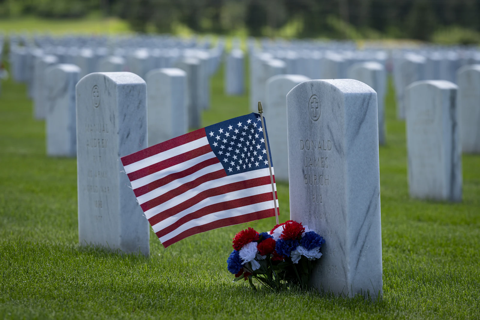 American flag and flowers placed at a veteran's headstone for Memorial Day