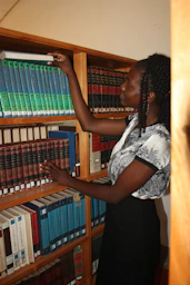 a woman standing in front of a book shelf filled with books