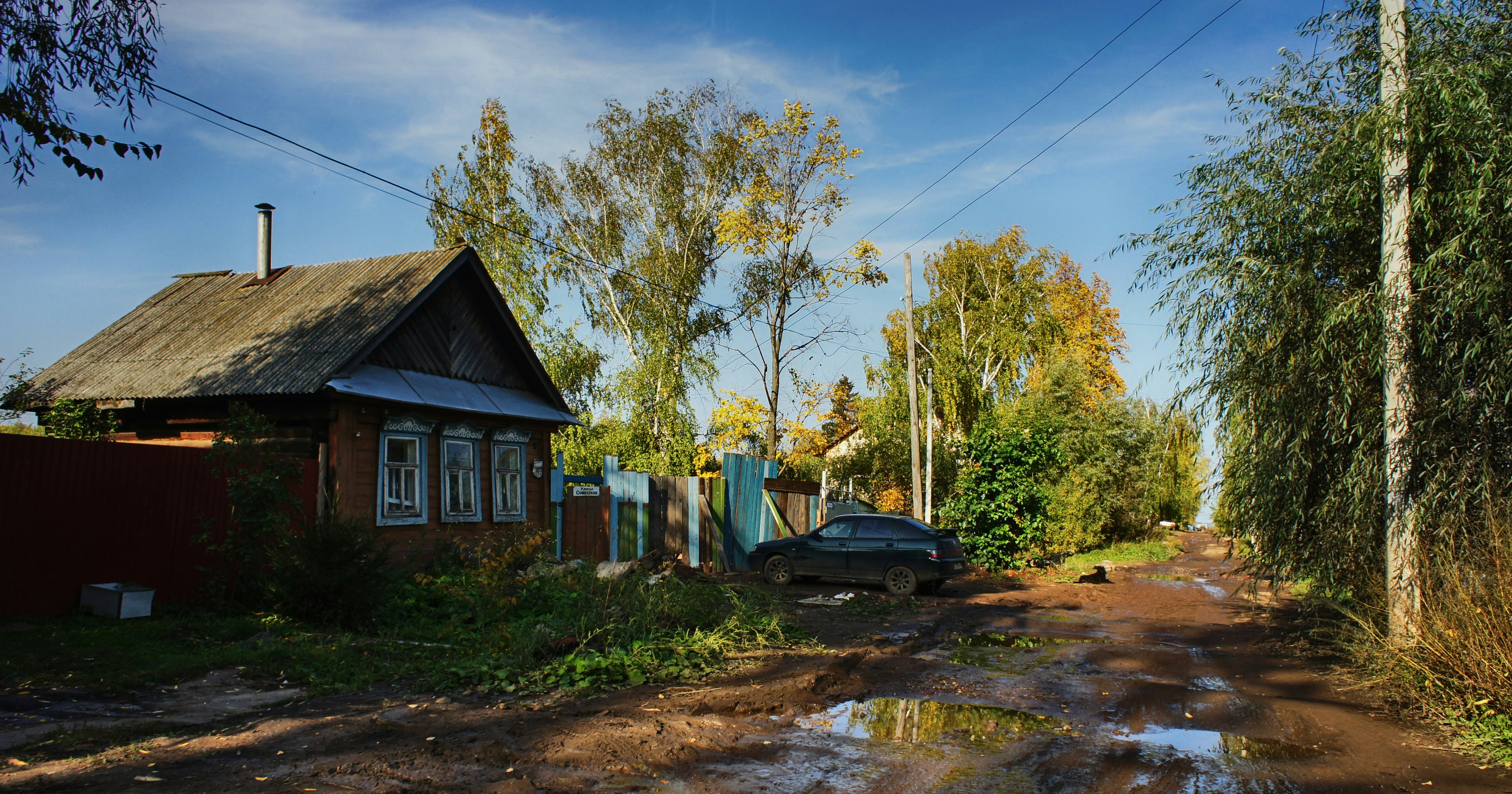 a car parked on a muddy road next to a house