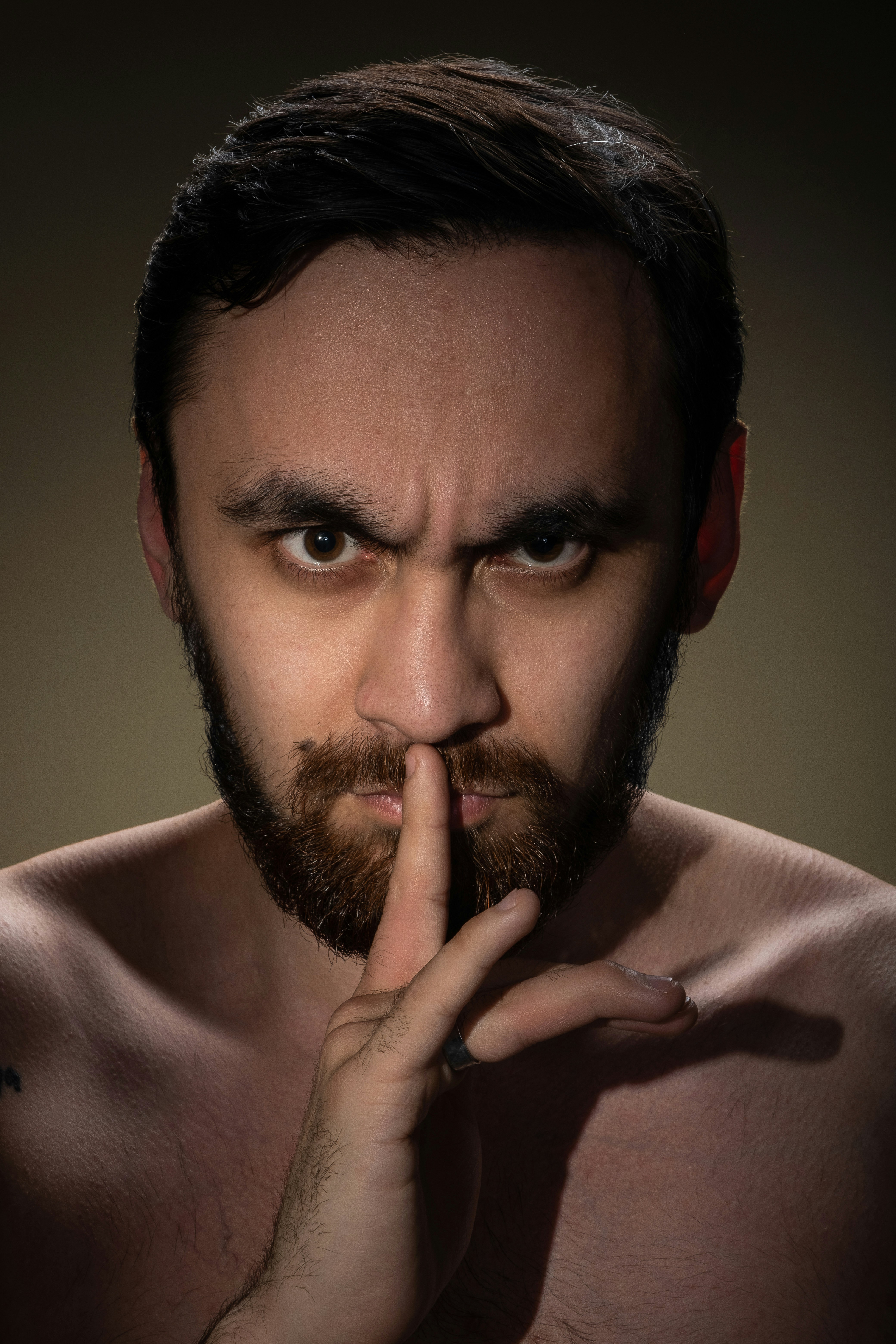 ein Mann ohne Hemd, der mit dem Finger schweigt