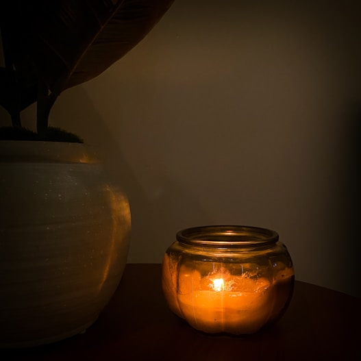 a lit candle in a glass jar on a table