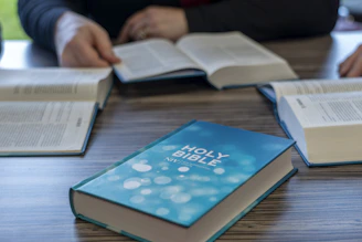 two people sitting at a table with open books