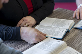two people sitting at a table with open books