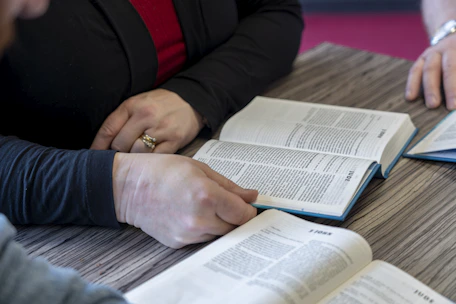 two people sitting at a table with open books