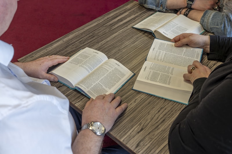 Group of people sitting at a table with open books in a study session