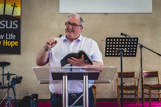 a man standing at a podium holding a book