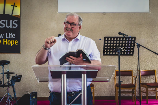 a man standing at a podium holding a book