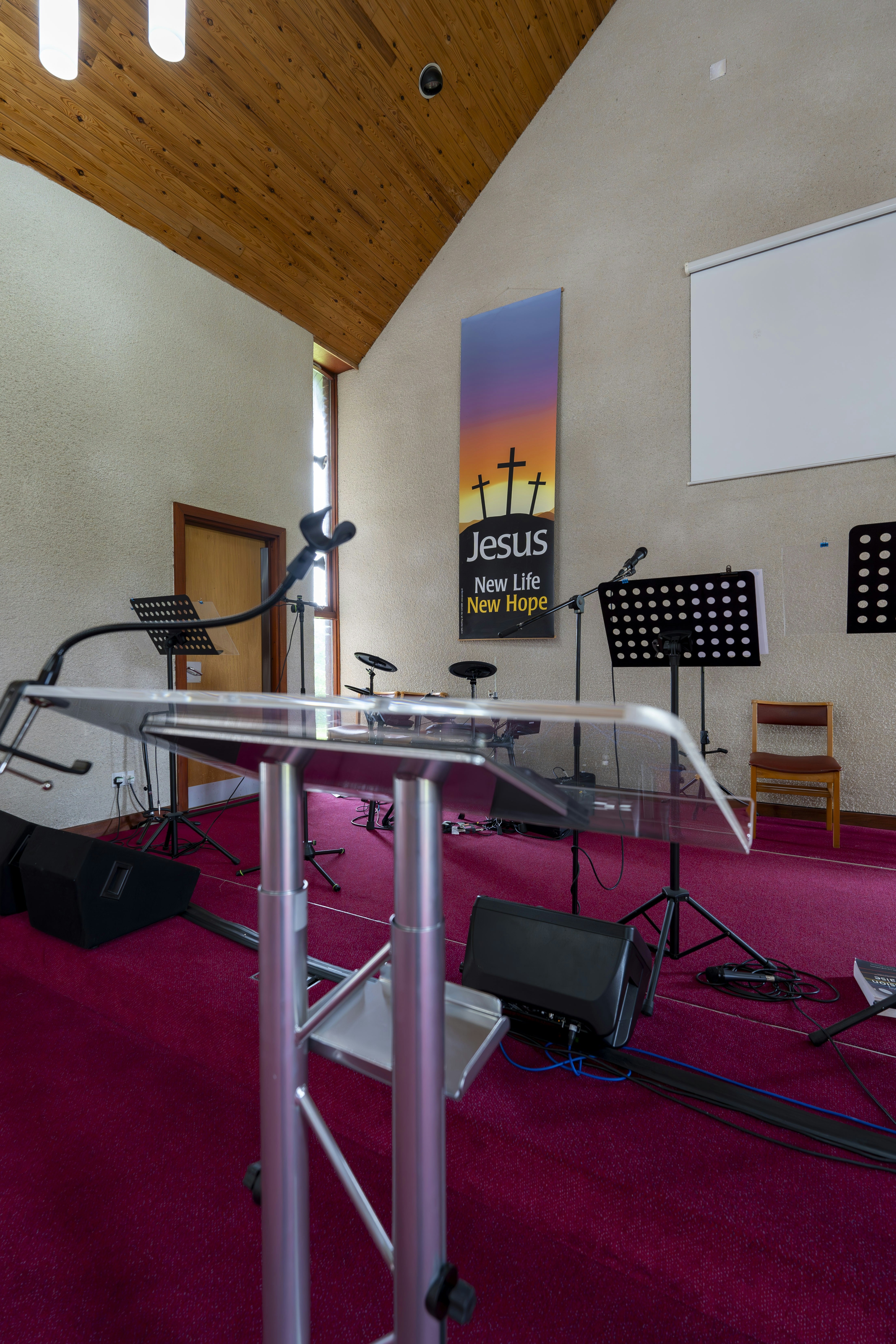 Acrylic podium stands on a stage with musical equipment.