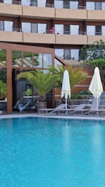 a hotel pool with lounge chairs and umbrellas