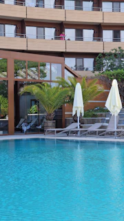 a hotel pool with lounge chairs and umbrellas