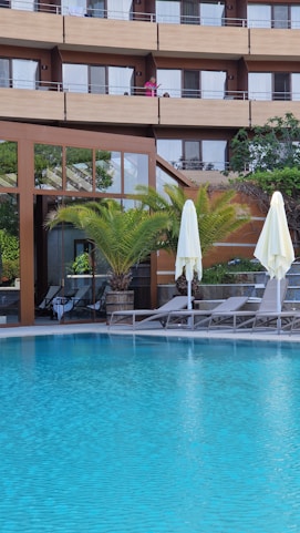a hotel pool with lounge chairs and umbrellas