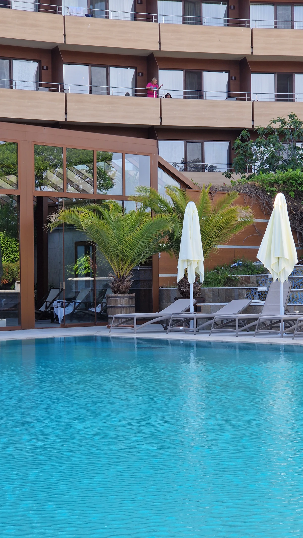 Resort style pool with loungers and umbrellas among greenery
