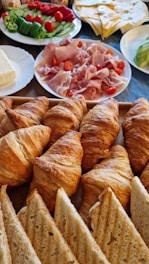 a table filled with croissants, breads, and salads