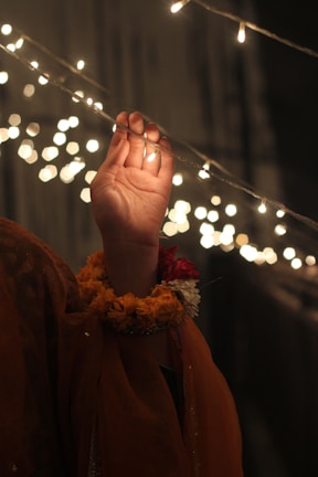a person holding their hand up in front of a string of lights