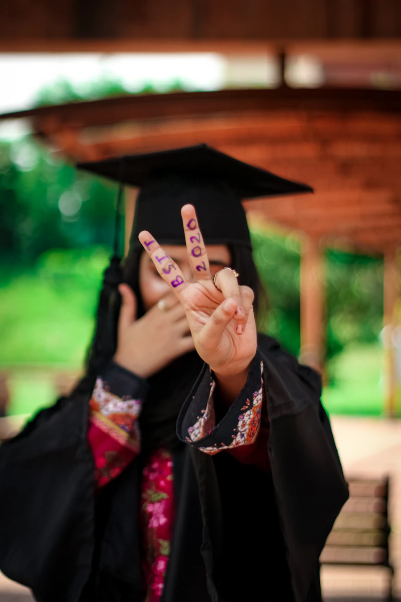 Young woman in a graduation gown making a peace sign
