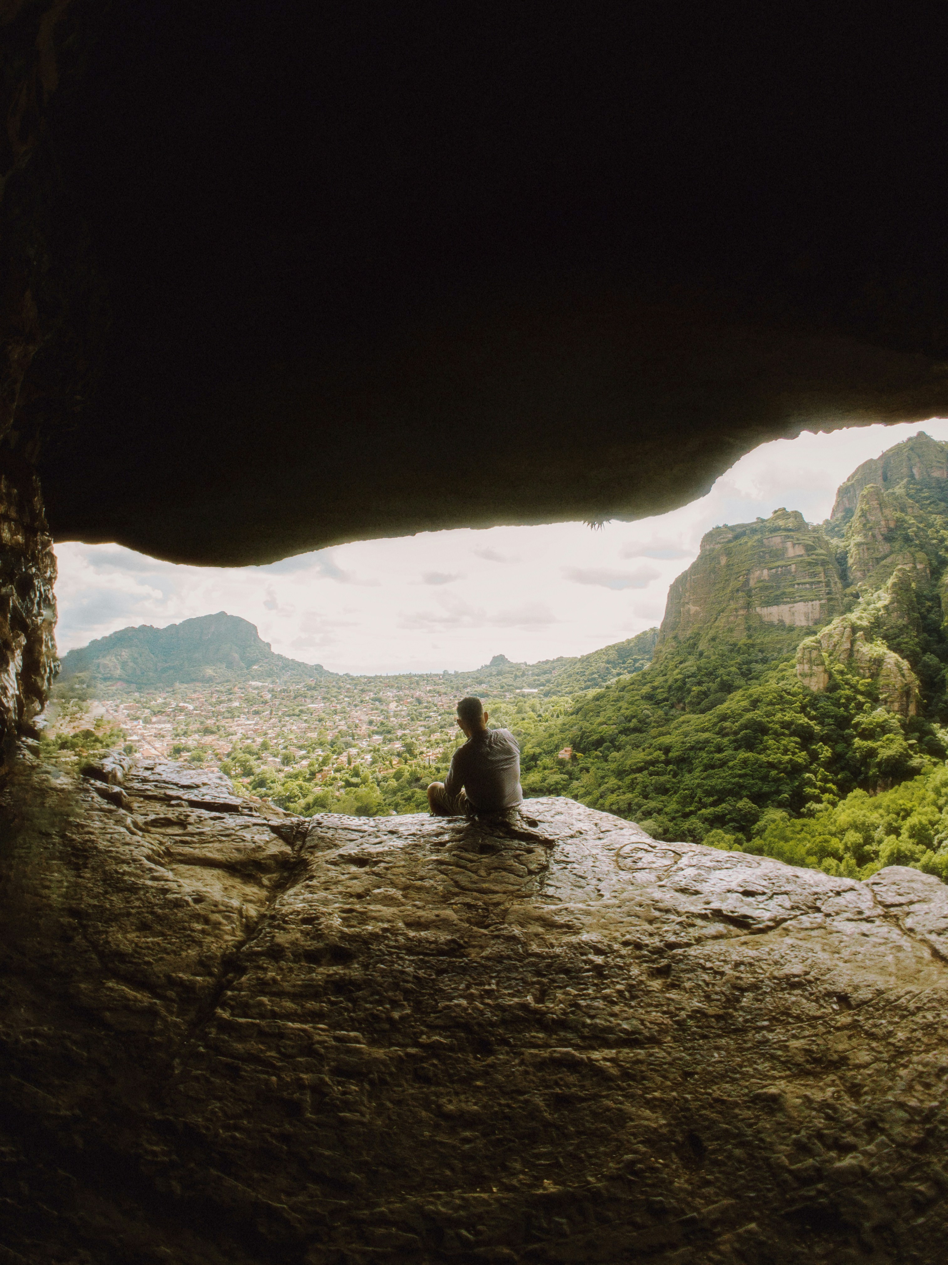 a person sitting on a rock looking out into a valley