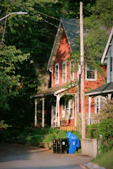 a red house with a blue trash can in front of it