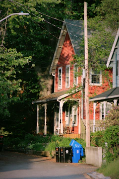 a red house with a blue trash can in front of it