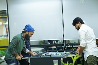 two men playing a game of foo - pong in an office