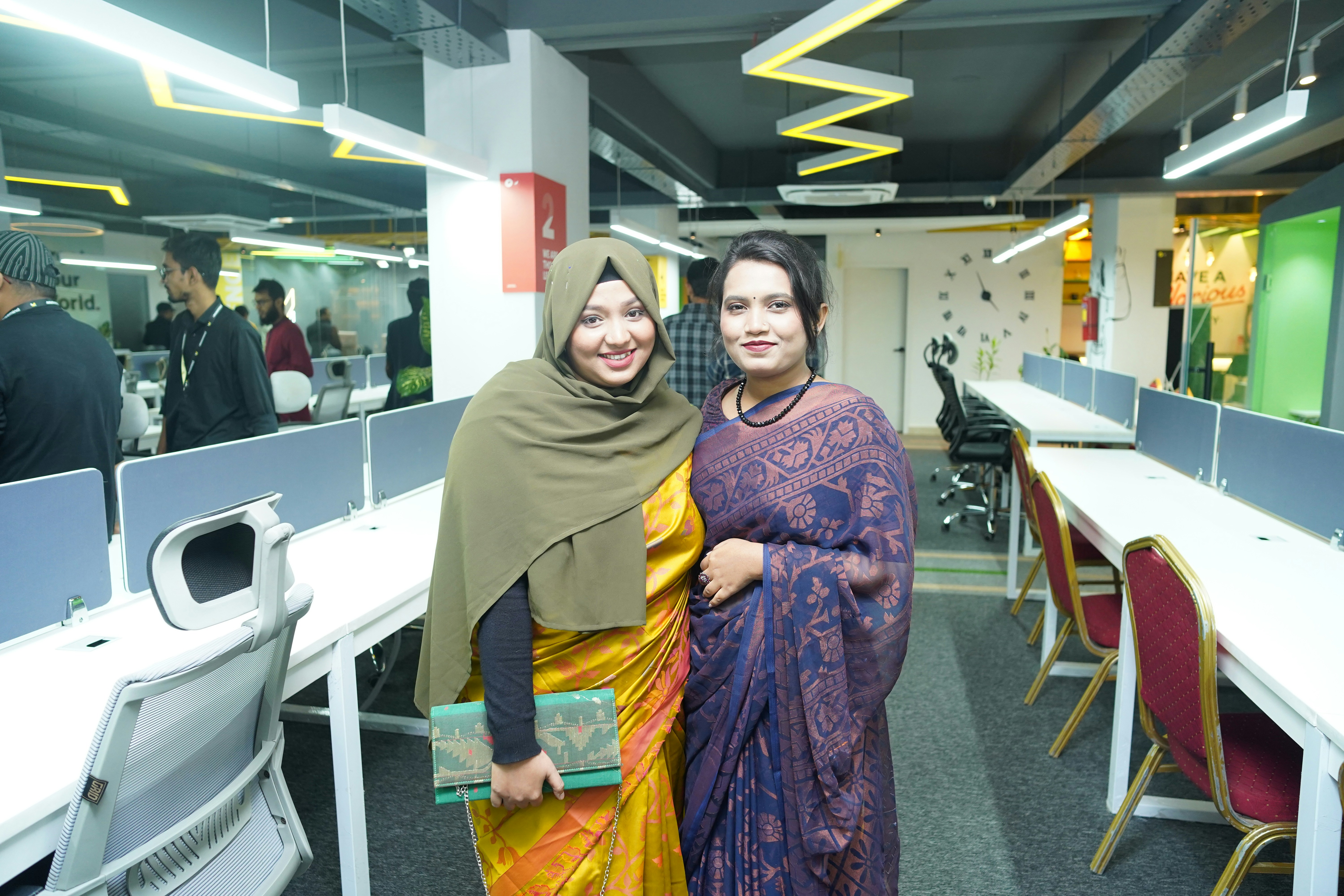 two women standing next to each other in an office