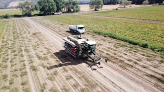 a couple of trucks driving down a dirt road