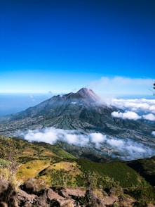 a view of a mountain with clouds and a blue sky